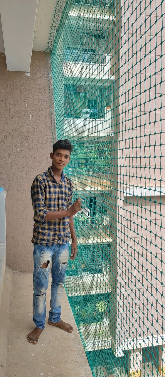 Green safety net installation on an apartment balcony